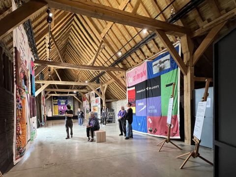 Timber-roofed hall with large printed banners and visitors.