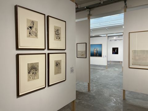 Framed works carefully hung in a white gallery room.